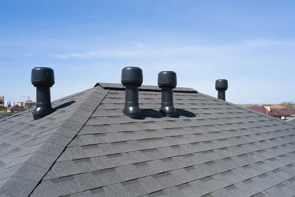 A roof with multiple chimneys under a cloudy sky.