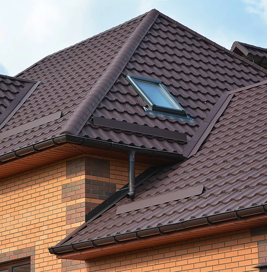 Durable brown metal roofing on a modern brick house with skylight, installed by professional roofing service