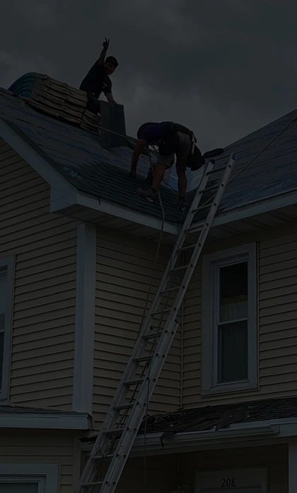 Roofing crew working on a two-story beige house, installing underlayment in preparation for new shingles.