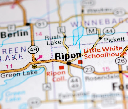 Close-up of a printed map highlighting Ripon, Wisconsin, including nearby landmarks like Rush Lake, Green Lake, and the Little White Schoolhouse.