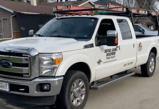 A white truck with a ladder on the side, parked and displaying the text "748-9371 W692."