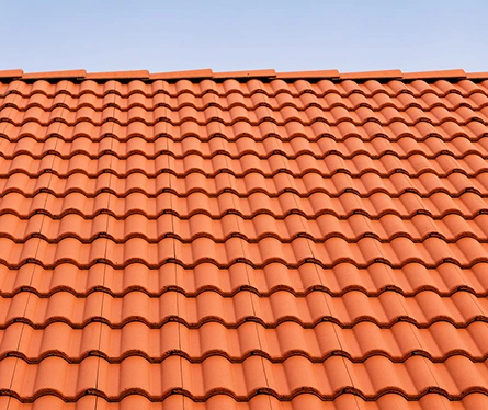 Close-up of a red ceramic tile roof under a clear blue sky