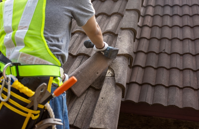 Worker man replace tile of the old damaged roof