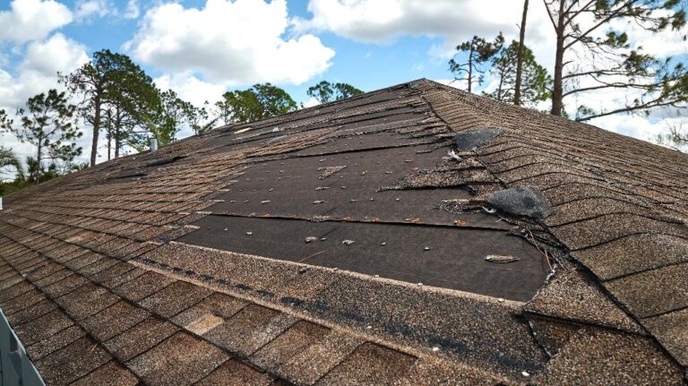 damaged house roof with missing asphalt shingles